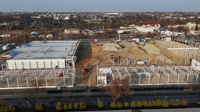 Aerial view of a large construction site for a modern industrial warehouse with steel frames and cranes. Wide panorama of an investment area, earthworks, foundations, and logistics infrastructure deve