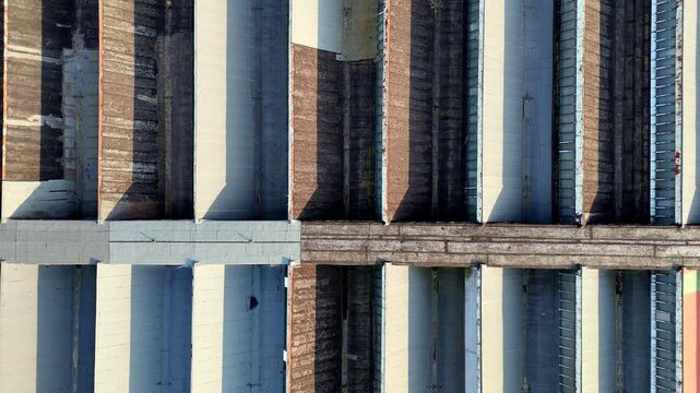 Aerial top-down view of an industrial sawtooth roof with weathered concrete textures, rust, and geometric patterns. Perfect for architectural photography, urban decay concepts, construction, and indus
