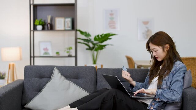 Asian Woman Using Credit Card for Online Shopping on Laptop at Home