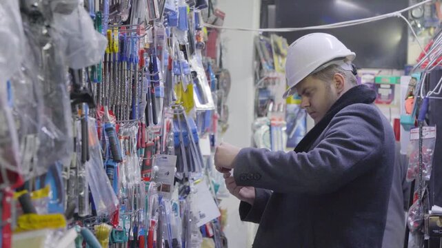 Man in hard hat choosing tools in a hardware store