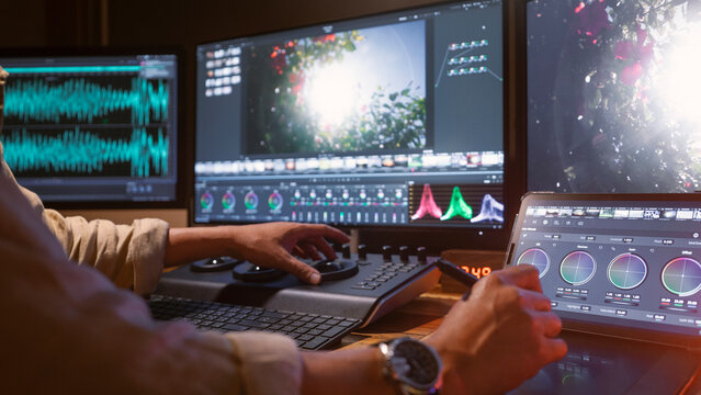 An Asian color grading technician is adjusting colors to be accurate and precise for a new nature-themed film in his state-of-the-art studio.