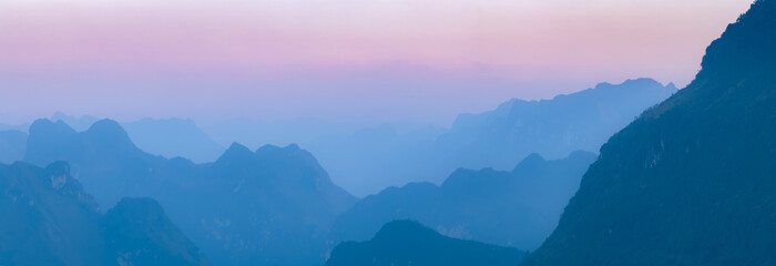 Fototapeta premium A scenic view of the mountains in Dong Van, Ha Giang, Vietnam, at dusk. The landscape shows the natural beauty of the region, with layers of mountains fading into the horizon.