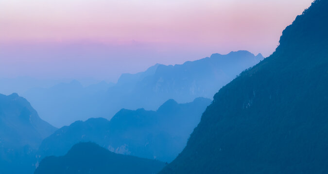 A scenic view of the mountains and valleys in Dong Van, Ha Giang Province, Vietnam, showcasing the natural beauty and landscape of the region at dusk.