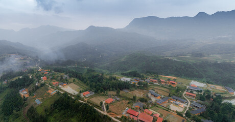 Obraz premium An aerial view shows the rural village of Quan Ba, Ha Giang, Vietnam, nestled in a valley surrounded by lush green mountains on an overcast day. ,