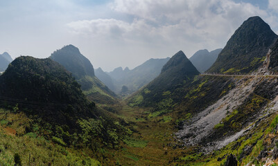 Fototapeta premium A scenic view of the mountains in Dong Van, Ha Giang, Vietnam. The landscape is lush and green, with a road winding through the mountains. A popular destination for tourists.