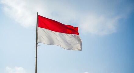 Naklejka premium Indonesian Flag Waving Proudly Against a Bright Blue Sky with Light Clouds, Symbolizing National Pride and Freedom
