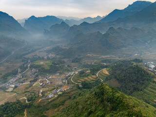 Fototapeta premium An aerial view of the mountains and valleys in Du Gia, Yen Minh, Ha Giang, Vietnam, showcasing the natural beauty and rural landscape of the region, with small villages nestled within.