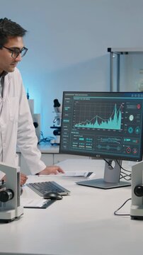 Scientists analyzing data on computer screen in modern laboratory, vertical footage