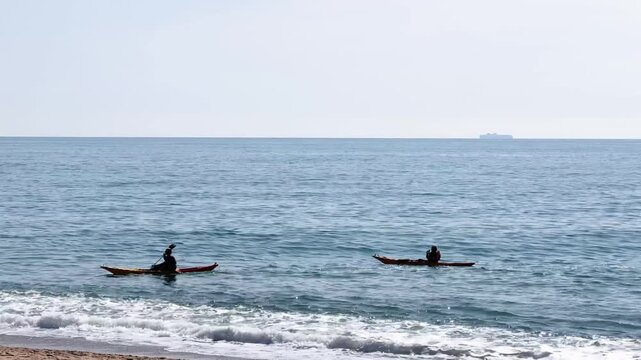 Two kayakers paddling calm Mediterranean Sea Spain horizon water sports adventure
