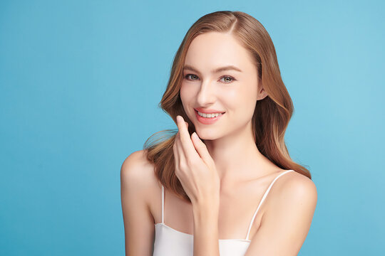 A beautiful young woman with clean, fresh skin against a blue background. Skincare, facial treatment, cosmetology, beauty, and spa. An elegant portrait of an woman.