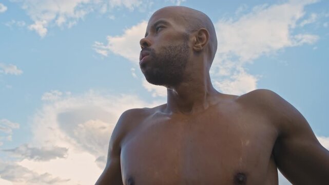 Man, runner and outdoor with strap for heart rate, monitor and low angle with break for fitness. African person, wearable tech and rest with breathing, thinking and shirtless for exercise in summer