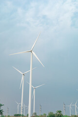 Fototapeta premium Low angle view of wind turbines against soft blue sky with minimal composition, representing clean renewable energy and modern sustainable power infrastructure.