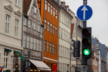 Urban street scene featuring colorful buildings with green traffic light and directional sign in a European city, showcasing architectural diversity and urban infrastructure
