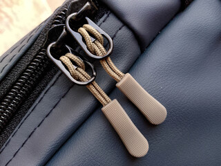 Close-up of Black Leather Bag with Tan Zipper Pulls and Metal Buckles