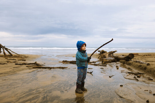 A toddler plays on the beach on a cold day.