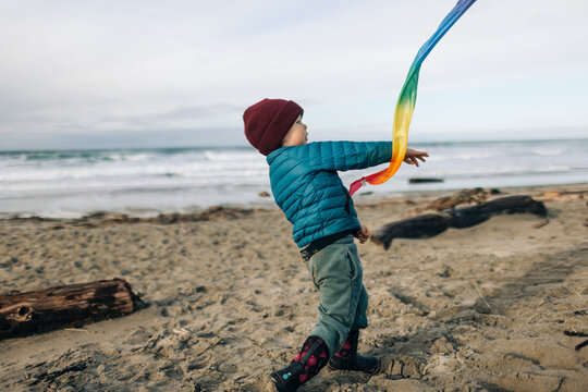 A young boy throws a ball on a beach.
