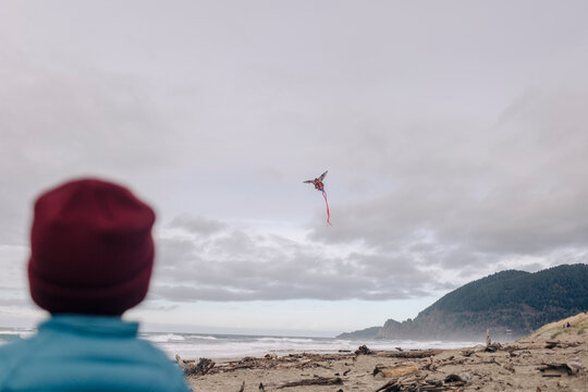 A toddler flies a kite on a beach in Oregon.