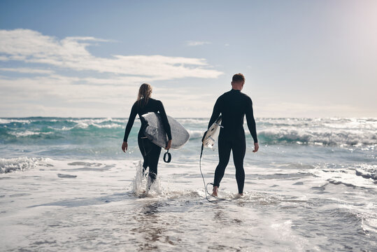 Vacation, couple or walking with surfboard in ocean for surfing adventure, weekend trip or bonding. Surfers, space or back of people on holiday for travel hobby, explore beach destination and support