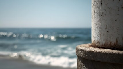 Fototapeta premium Close up of a textured stone pillar against a blurred backdrop of the calm ocean and bright sky