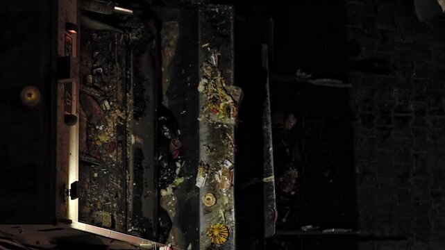 Detailed shot of household waste material being compacted inside garbage truck during nighttime collection, showcasing trash and refuse within mechanical compactor