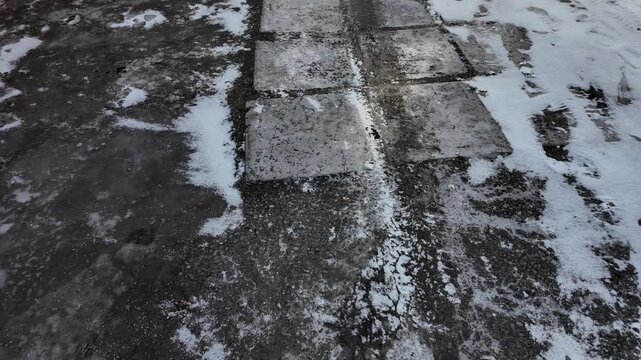 Early spring thaw on a frozen road. Footprints and tracks mark the slippery, melting ice.