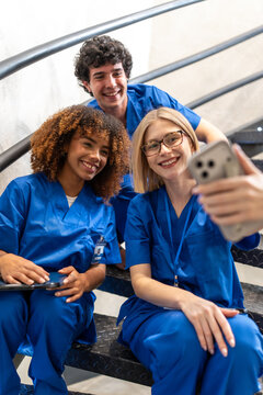 Diverse medical students team taking happy selfie on stairs