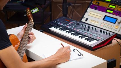 male musician writing a hit song by acoustic guitar in home studio. songwriting concept