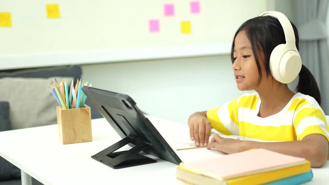 Asian girl with headphones enjoying online class on digital tablet