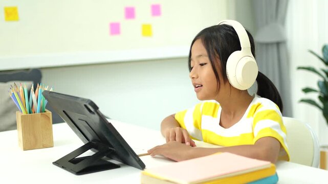 Asian girl with headphones enjoying online class on digital tablet