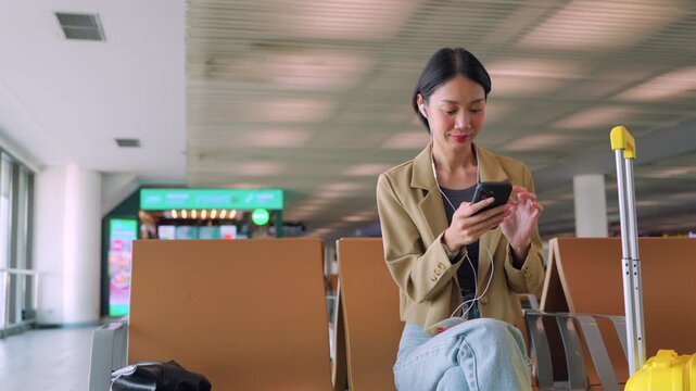 Asian woman starts her morning routine at the airport gate, listening to a podcast on her phone while waiting for departure. Concept of journey and solo travel.