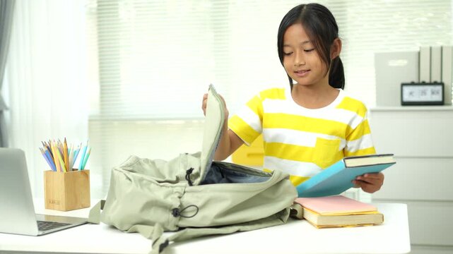 Girl packing the book into bag. Girl prepare to school pack bag.