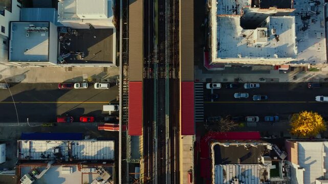 Top-down aerial drone view of elevated train tracks between buildings in Brooklyn creating strong geometric patterns and symmetry, filmed in ProRes 422HQ.