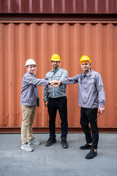 Engineer industrial workers males teamwork hands together in shipping container logistics warehouse