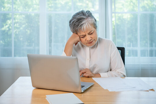 Serious Asian senior female manager working from home, business stress, remote office lifestyle and professional burnout concept