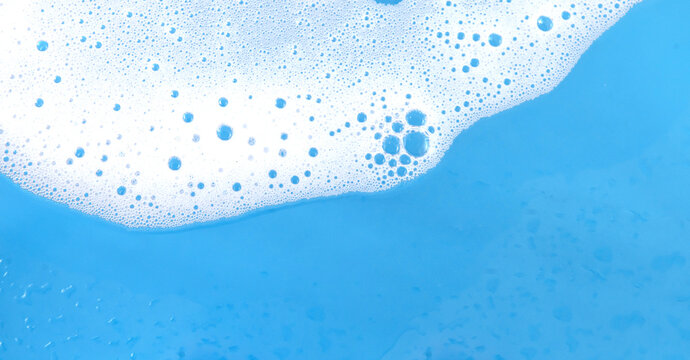 White cleaning foam on blue background, active chemical detergent and surface sanitizing concept