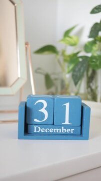 A close up view of a blue wooden desk calendar showing December 31st, symbolizing the end of the year and new beginnings