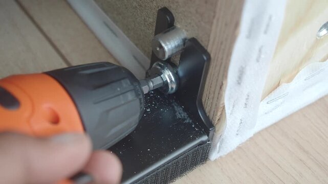 Fixing a furniture hinge with a drill in a home workshop