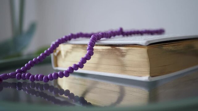 A quran with a prayer bead necklace on a table