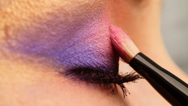 Make-up artist applies makeup to the upper eyelid, close-up.  Makeup artist applies a bright eye shadow with a makeup brush. Tutorial master class of professional makeup.