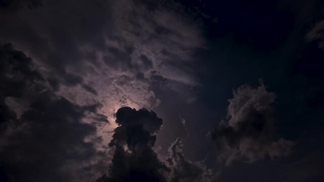 Full moon shining through dark dramatic clouds at night