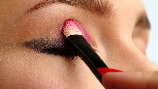 Make-up artist applies makeup to the upper eyelid, close-up.  Makeup artist applies a bright eye shadow with a makeup brush. Tutorial master class of professional makeup.