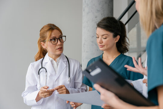 Doctor and nurse discussing medical documents during hospital meeting