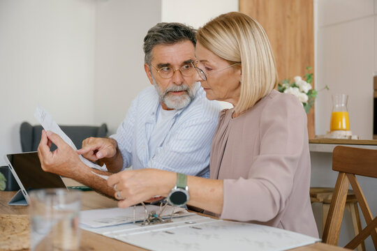 Couple discussing financial bills together at home kitchen table