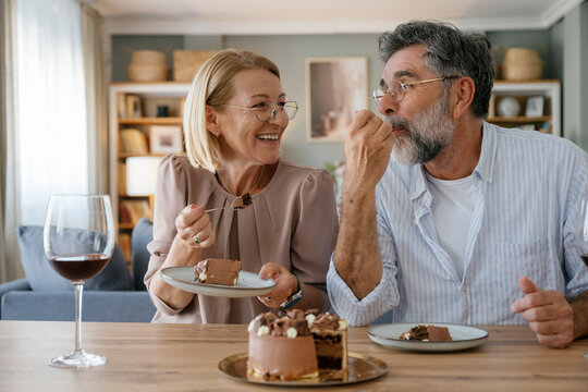 Happy senior couple eating cake and celebrating at home