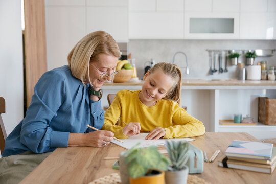 Grandmother and child doing homework together at home in kitchen