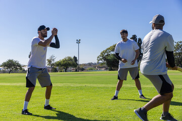 Obraz premium Three men wearing white tees practicing batting drill on local field with bat, copy space