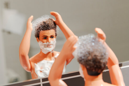 Toy with foam on hair and face in bathroom mirror mimicking grooming