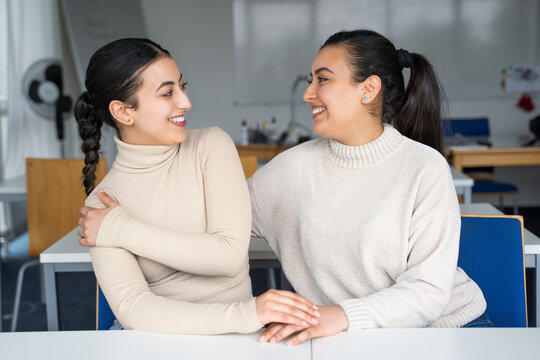 Two sisters smiling at each other in a classroom setting