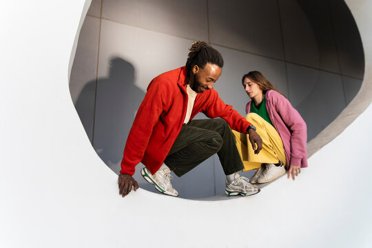 Fashionable pair posing beside a white circle outdoors