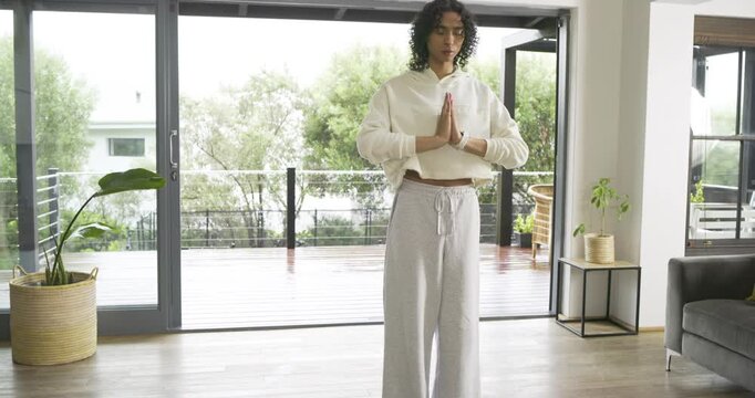 Camera panning showing non-binary adult holding prayer pose on green yoga mat breathing mindfully
